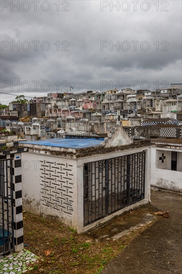 Famous cemetery, many mausoleums or large tombs decorated with tiles, often in black and white. Densely built buildings under a dramatic cloud cover Cimetiere de Morne-a-l'eau, Grand Terre, Guadeloupe, Caribbean, North America