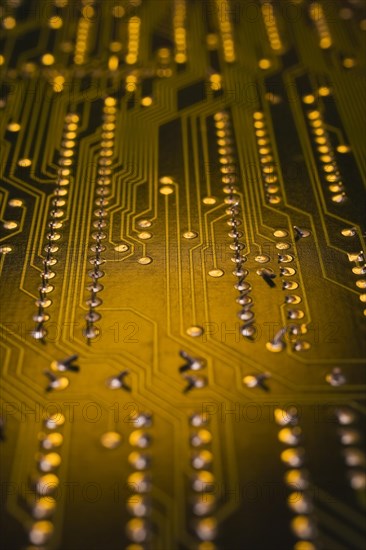 Close-up of golden yellow lighted electronic computer circuit board with lines and silver solder points, Studio Composition, Quebec, Canada, North America