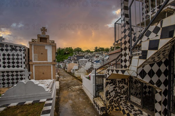 Famous cemetery, many mausoleums or large tombs decorated with tiles, often in black and white. Densely built buildings under a sunset Cimetiere de Morne-a-l'eau, Grand Terre, Guadeloupe, Caribbean, North America