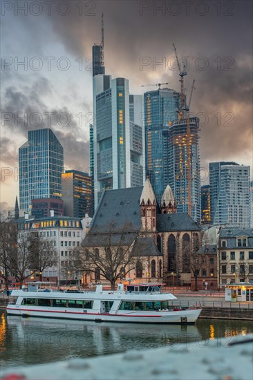 Sunrise on a riverbank in the centre of a big city. Spring with a view of the skyline of the banking district and the historic buildings of Frankfurt, Hesse