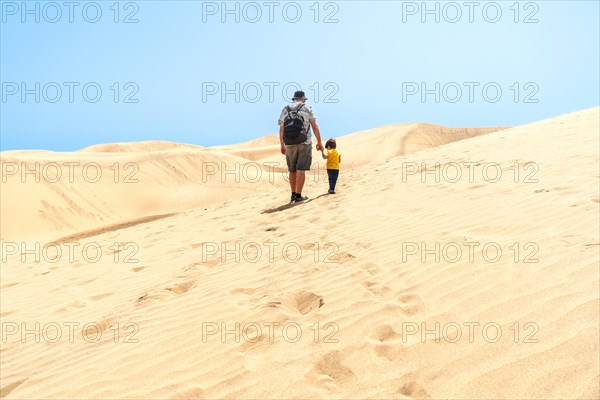 Father and son on vacation laughing running in the dunes of Maspalomas, Gran Canaria, Canary Islands