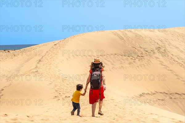 Mother and child walking in the dunes of Maspalomas in summer, Gran Canaria, Canary Islands
