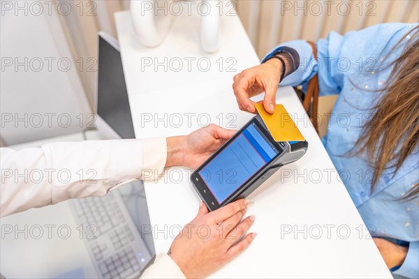 Top view of an unrecognizable woman paying with credit card in a beautician clinic
