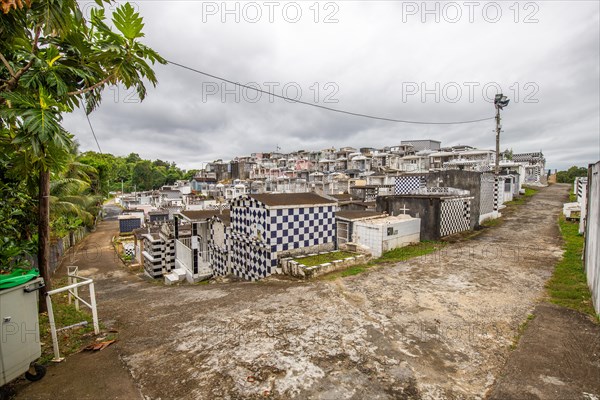 Famous cemetery, many mausoleums or large tombs decorated with tiles, often in black and white. Densely built buildings under a dramatic cloud cover Cimetiere de Morne-a-l'eau, Grand Terre, Guadeloupe, Caribbean, North America