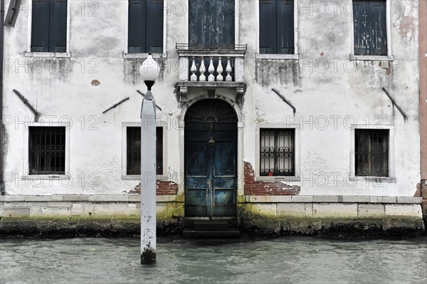 Weathered building on the waterfront in Italy with striking blue door, Venice, Veneto, Italy, Europe
