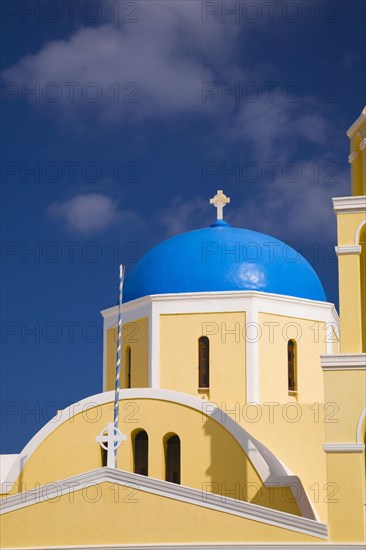 Close-up of yellow painted roughcast cladded chapel with cross on blue dome, Oia village, Santorini, Greece, Europe