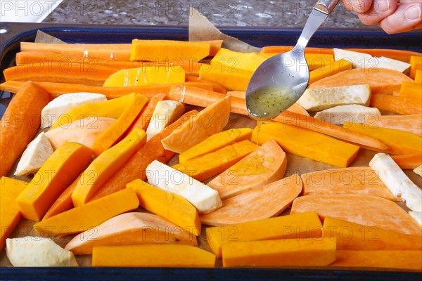 South German cuisine, butternut squash, butternut squash, pumpkin drizzled with olive oil, vegetables cut on baking tray, preparation of oven vegetables, pumpkin, fruit vegetables, fruit, carrots, celery, healthy cooking, vegetarian, vegan, autumn cuisine, pumpkin dishes, food, studio, man's hand, tablespoon, Germany, Europe