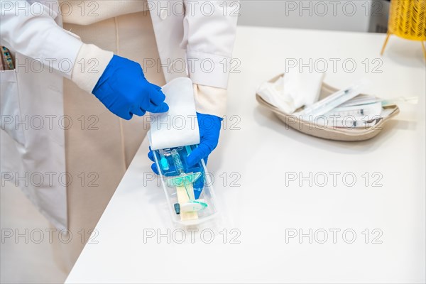 Top view photo of a surgeon with protective blue latex gloves preparing a hyaluronic acid injection in the clinic