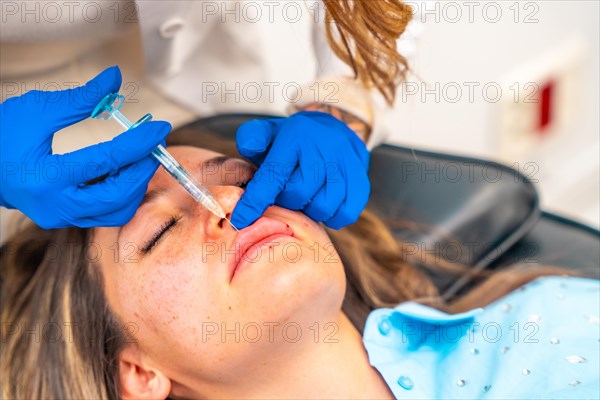 Close-up of a caucasian adult woman getting a Botox injection in the lips in a beautician professional clinic