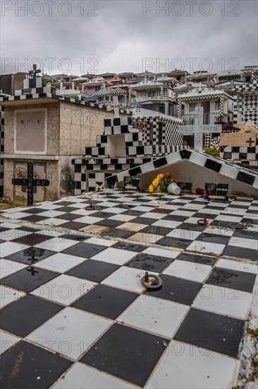 Famous cemetery, many mausoleums or large tombs decorated with tiles, often in black and white. Densely built buildings under a dramatic cloud cover Cimetiere de Morne-a-l'eau, Grand Terre, Guadeloupe, Caribbean, North America