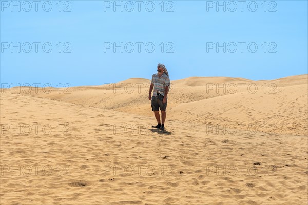 Portrait of male tourist in summer walking in the dunes of Maspalomas, Gran Canaria, Canary Islands