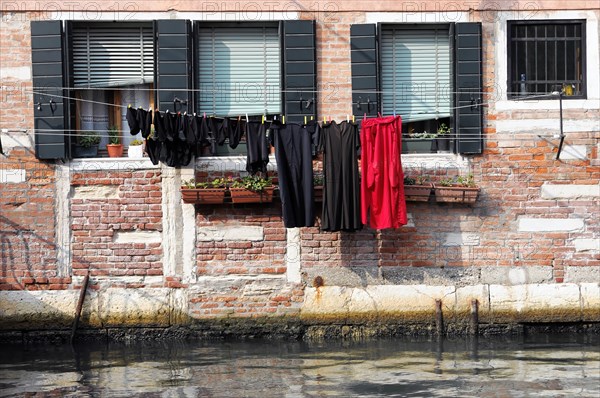 Laundry hanging outside to dry on a brick wall above the water, Venice, Veneto, Italy, Europe