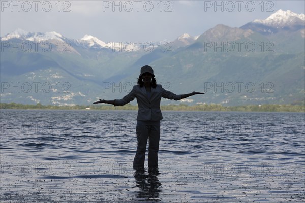 Woman Standing in a Flooding Alpine Lake Maggiore with Snowcapped Mountain in Locarno, ticino, Switzerland. | MR:yes Maria-CH-20-04-2022