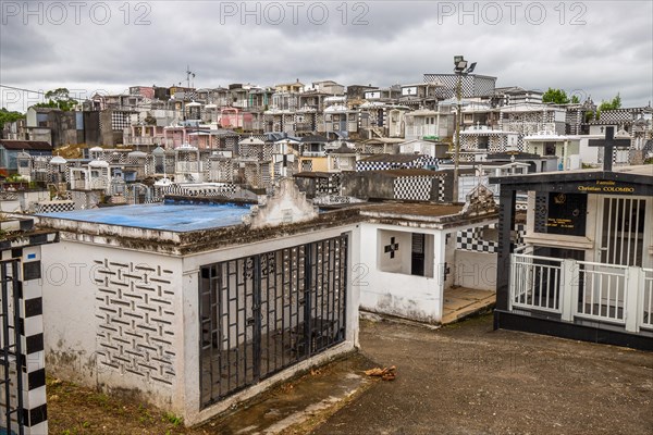Famous cemetery, many mausoleums or large tombs decorated with tiles, often in black and white. Densely built buildings under a dramatic cloud cover Cimetiere de Morne-a-l'eau, Grand Terre, Guadeloupe, Caribbean, North America