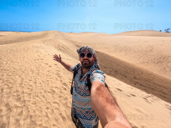 Selfie of a tourist with sunglasses and turban enjoying in the dunes of Maspalomas, Gran Canaria, Canary Islands