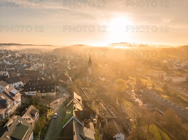 A church tower stands out as the town awakens in the sunrise light, Gechingen, Black Forest, Germany, Europe