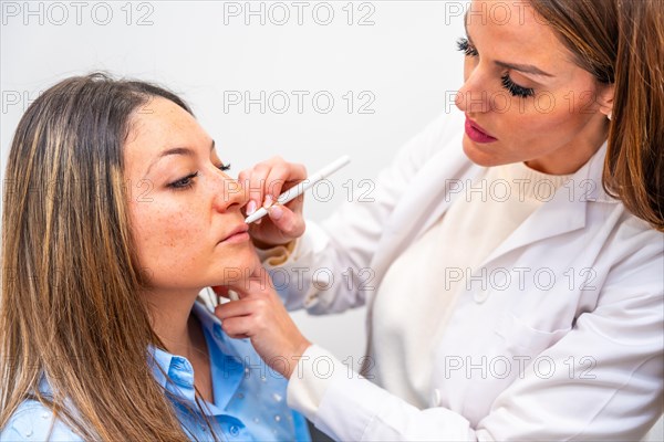 Female doctor marking with a pencil the lines where to inject hyaluronic acid on the face of a mature woman