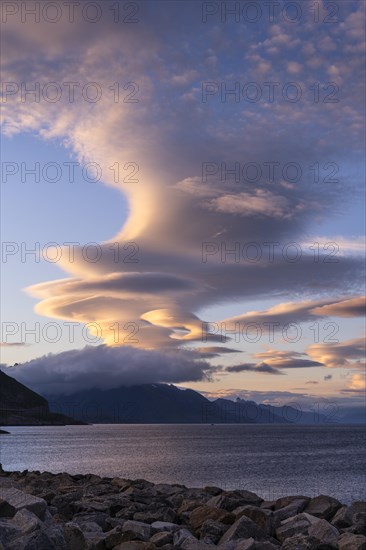 Cloudscape, view from Hamnoy over the sea along Moskenesoya, Flakstadoya and Vestvagoya. Several lenticular clouds (lenticularis) in the blue sky. At night at the time of the midnight sun in good weather. Early summer. Lofoten, Norway, Europe