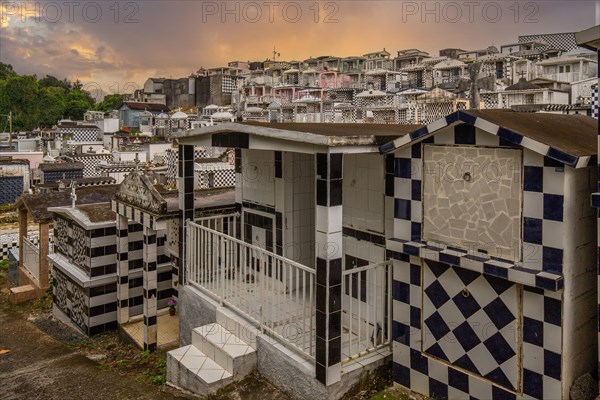 Famous cemetery, many mausoleums or large tombs decorated with tiles, often in black and white. Densely built buildings under a sunset Cimetiere de Morne-a-l'eau, Grand Terre, Guadeloupe, Caribbean, North America