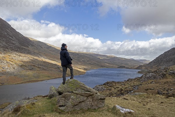 Man standing on stone, Lake Llyn Ogwen, Snowdonia National Park near Pont Pen-y-benglog, Bethesda, Bangor, Wales, Great Britain