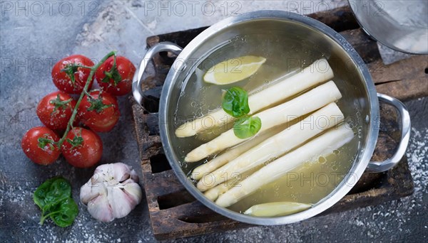 A pot of asparagus and lemon slices surrounded by fresh ingredients, fresh white asparagus in a cooking pot, KI generated, AI generated