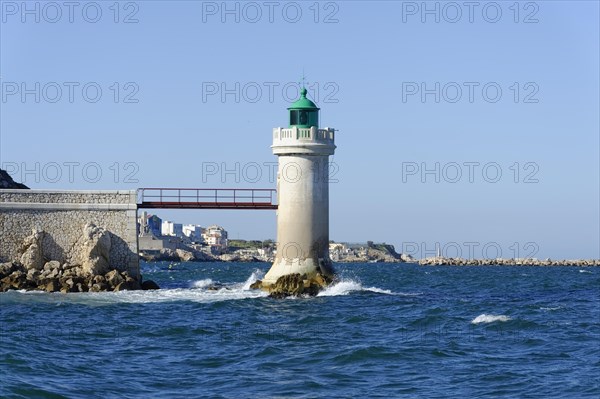 Lighthouse stands on rocky coast with rough sea and clear sky, Marseille, Departement Bouches-du-Rhone, Region Provence-Alpes-Cote d'Azur, France, Europe
