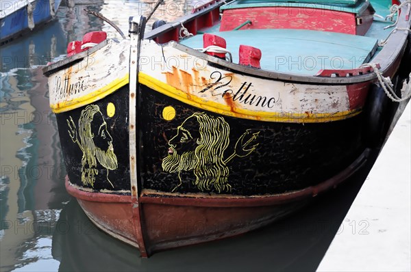 The painted front of a boat with a lion's head motif on calm water, Burano, Venice, Veneto, Italy, Europe