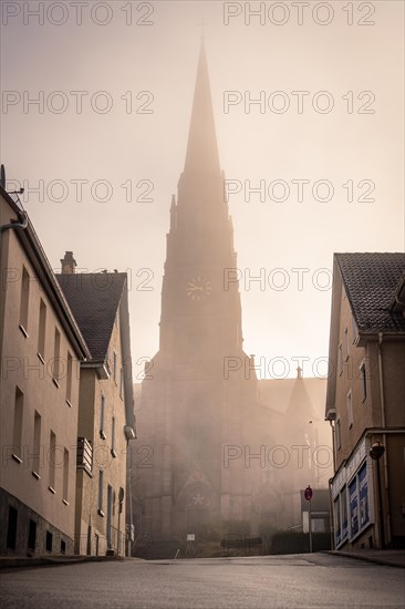 Morning fog envelops a church spire in an urban scene, faint sunlight penetrates, sunrise, Nagold, Black Forest, Germany, Europe