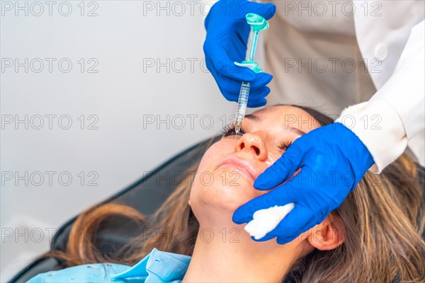 The doctor cosmetologist makes the rejuvenating facial injections procedure for tightening and smoothing wrinkles on the face skin of a beautiful woman in a clinic