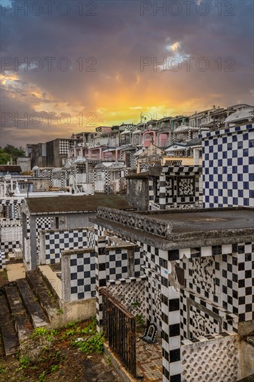 Famous cemetery, many mausoleums or large tombs decorated with tiles, often in black and white. Densely built buildings under a sunset Cimetiere de Morne-a-l'eau, Grand Terre, Guadeloupe, Caribbean, North America