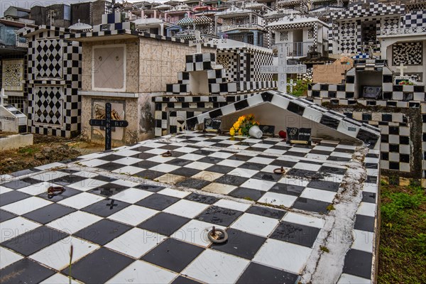 Famous cemetery, many mausoleums or large tombs decorated with tiles, often in black and white. Densely built buildings under a dramatic cloud cover Cimetiere de Morne-a-l'eau, Grand Terre, Guadeloupe, Caribbean, North America