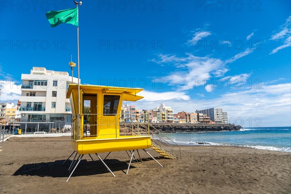 Yellow lifeguard tower in California with green flag