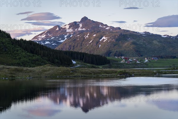 Landscape on the Lofoten Islands. Lake Holdalsvatnet, Mount Blatinden and other mountains in the background. The landscape is reflected in the lake. At night at the time of the midnight sun in good weather. Blue sky with a few coloured clouds. Vestvagoya, Lofoten, Norway, Europe