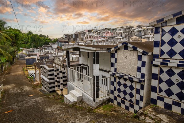 Famous cemetery, many mausoleums or large tombs decorated with tiles, often in black and white. Densely built buildings under a sunset Cimetiere de Morne-a-l'eau, Grand Terre, Guadeloupe, Caribbean, North America