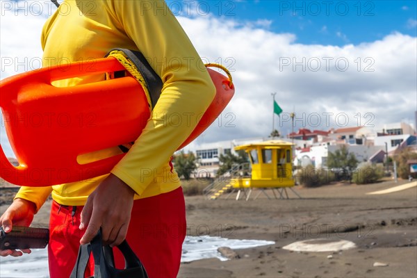 Baywatch with orange lifebuoy with beach rescue worker on the beach