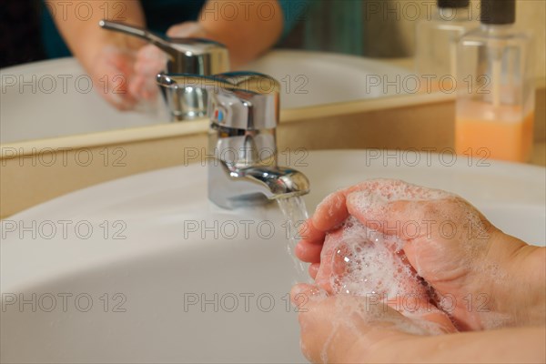 Closeup of a woman washing her hands with liquid soap suds in the bathroom sink. Hand hygiene from bacteria. Foam foams in women's hands