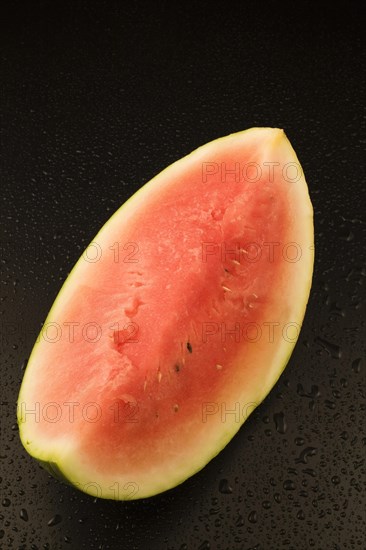 Top view and close-up of half a Citrullus lanatus, Watermelon on black background with water droplets, Studio Composition, Quebec, Canada, North America
