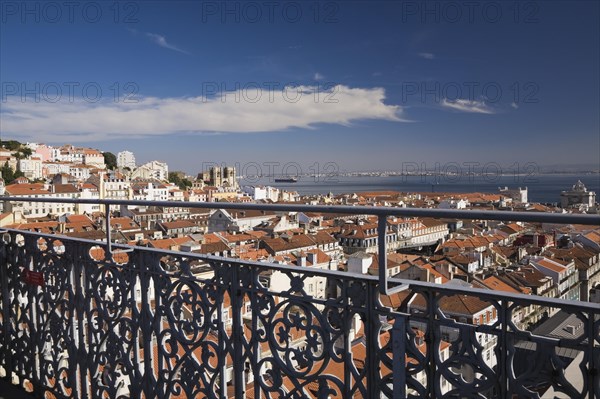 Grey wrought iron railing and high angle view of buildings with traditional terracotta tiled rooftops in old Lisbon from Santa Justa elevator observation platform, Lisbon, Portugal, Europe