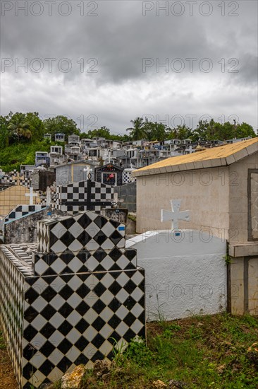 Famous cemetery, many mausoleums or large tombs decorated with tiles, often in black and white. Densely built buildings under a dramatic cloud cover Cimetiere de Morne-a-l'eau, Grand Terre, Guadeloupe, Caribbean, North America