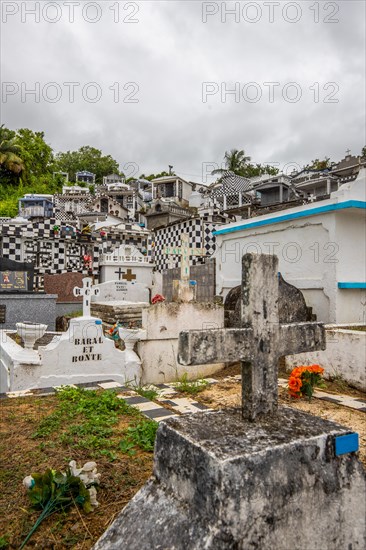 Famous cemetery, many mausoleums or large tombs decorated with tiles, often in black and white. Densely built buildings under a dramatic cloud cover Cimetiere de Morne-a-l'eau, Grand Terre, Guadeloupe, Caribbean, North America