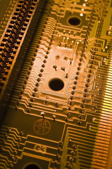 Close-up of golden orange and yellow lighted electronic computer circuit board with silver solder points and lines, Studio Composition, Quebec, Canada, North America