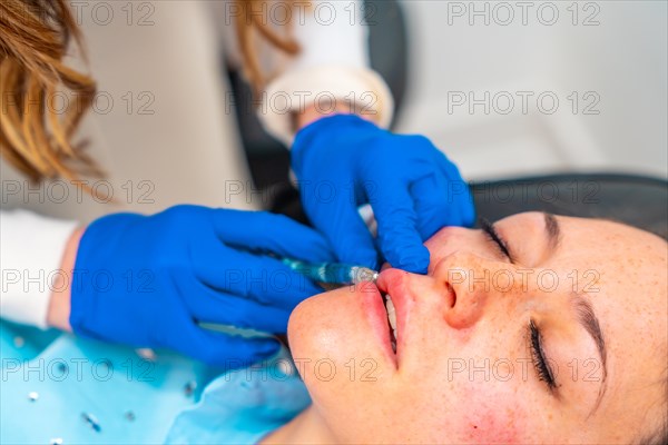 Woman receiving an injection to increase volume in the lips in a facial beautification procedure at the clinic