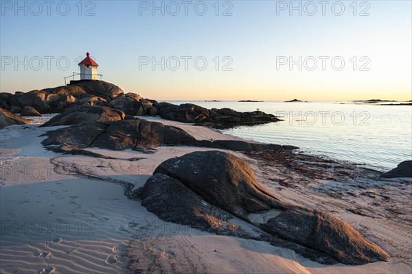 Seascape on the Lofoten Islands. The small lighthouse on the sandy beach of Eggum, sea and rocks. At night at the time of the midnight sun in good weather, blue sky. Golden hour. Early summer. Eggum, Vestvagoya, Lofoten, Norway, Europe