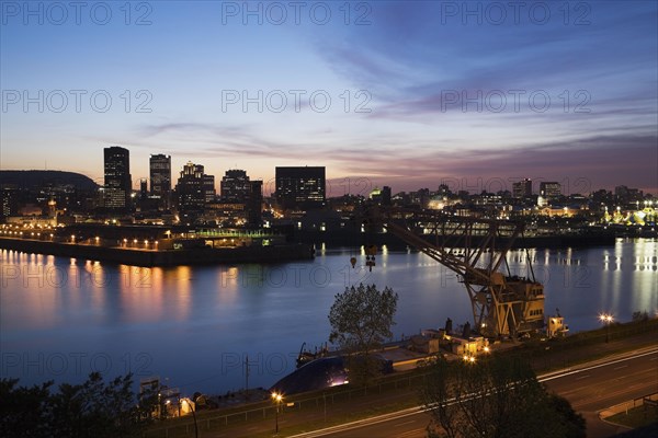 View of Pierre-Dupuy Avenue and Port of Montreal with city skyline showing old and modern architectural buildings illuminated at dusk, Montreal, Quebec, Canada, North America