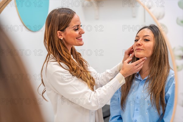 View from a mirror of a smiling aesthetic doctor analyzing the skin of an adult woman in the clinic