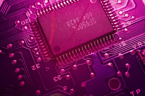 Close-up of purple lighted electronic computer circuit board with memory chip lines and silver solder points, Studio Composition, Quebec, Canada, North America