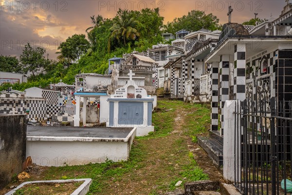 Famous cemetery, many mausoleums or large tombs decorated with tiles, often in black and white. Densely built buildings under a sunset Cimetiere de Morne-a-l'eau, Grand Terre, Guadeloupe, Caribbean, North America