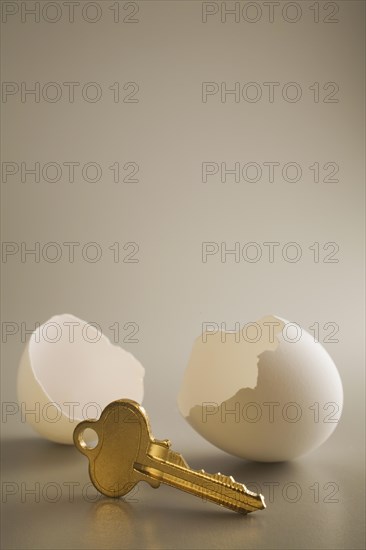 Close-up of antique brass key and two white cracked opened chicken egg shells on grey background, Studio Composition, Quebec, Canada, North America