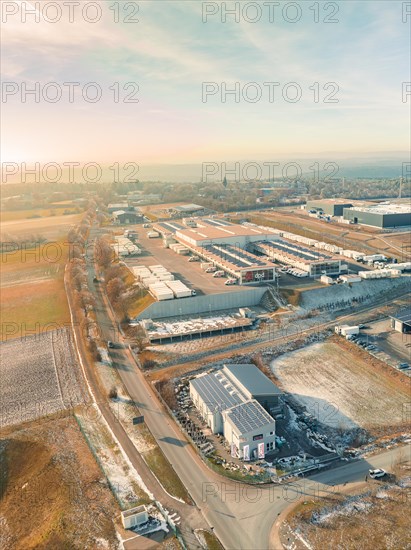 Sunlit aerial view of an industrial area with various warehouse buildings and streets, sunrise, Nagold, Black Forest, Germany, Europe