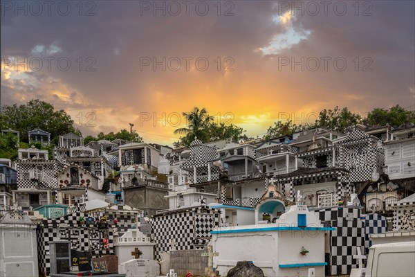 Famous cemetery, many mausoleums or large tombs decorated with tiles, often in black and white. Densely built buildings under a sunset Cimetiere de Morne-a-l'eau, Grand Terre, Guadeloupe, Caribbean, North America